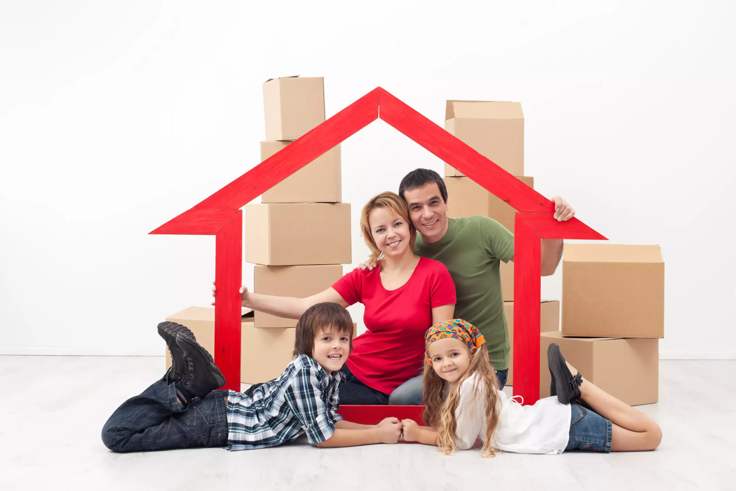 Young family holding up a red cutout of a home